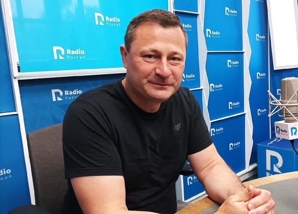 Krzysztof Paszyk podczas wystąpienia publicznego, gestykulujący, co symbolizuje jego aktywność w karierze politycznej i zawodowej.