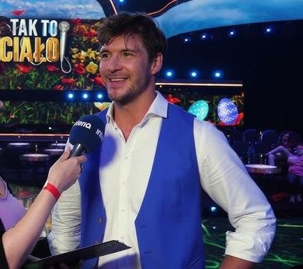 Scena teatralna z maską lalkarską, symbolizująca wykształcenie Mikołaja Roznerskiego na wydziale lalkarskim.