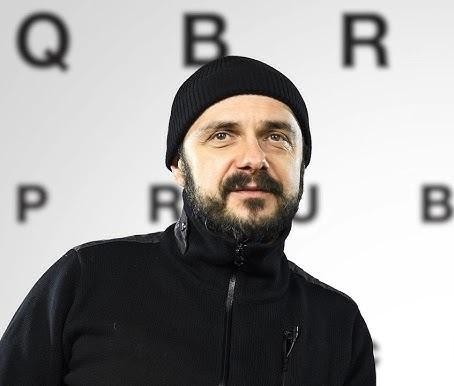 Arkadiusz Jakubik w dynamicznej pozie, symbolizującej jego wszechstronną karierę aktora, reżysera i muzyka.