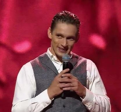 Filip Gurłacz w dynamicznej pozie na scenie telewizyjnej, podczas występu w programie rozrywkowym.