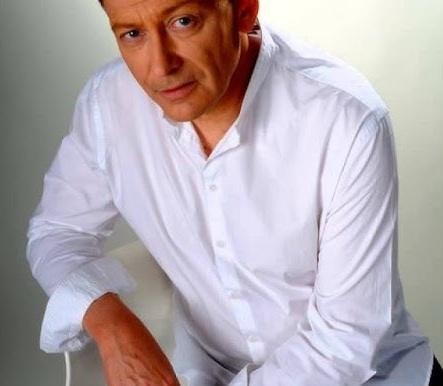 Jacek Borkowski w studiu nagraniowym, z mikrofonem i słuchawkami, symbolizujący jego pracę jako aktora dubbingowego.