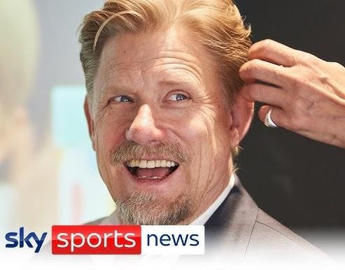 Peter Schmeichel broniący strzał, z widoczną determinacją na twarzy, w tle rozmazany stadion piłkarski.