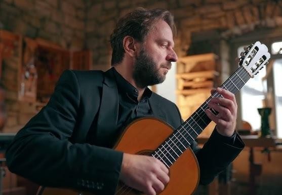 Zbliżenie na dłonie Marcina Dylli grającego na gitarze klasycznej, ukazujące precyzję jego techniki.