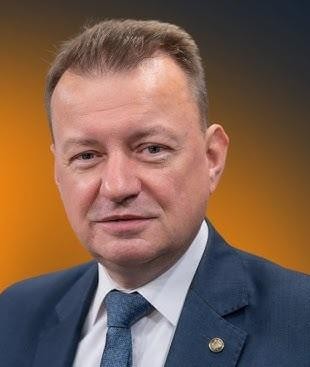 Czarna limuzyna rządowa z przyciemnianymi szybami, w tle wejście do kina lub czerwony dywan.