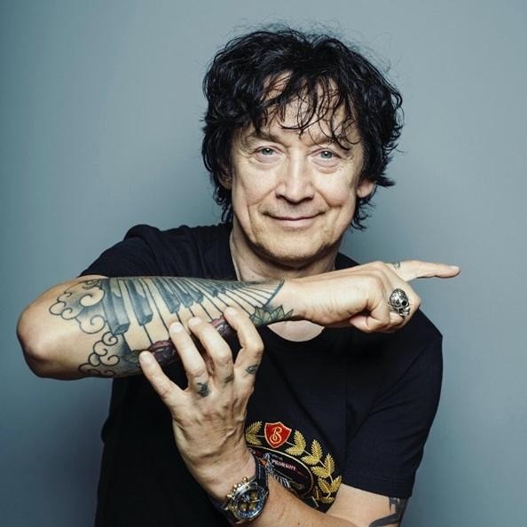 Jan Borysewicz grający na gitarze elektrycznej podczas koncertu, z widoczną energią sceniczną.