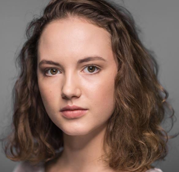 Martyna Byczkowska na planie filmowym, w charakteryzacji, w tle widoczne elementy scenografii.