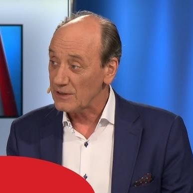Dariusz Szpakowski, uśmiechnięty i pełen pasji, w charakterystycznym geście podczas komentowania, podkreślający jego charyzmę i zaangażowanie.