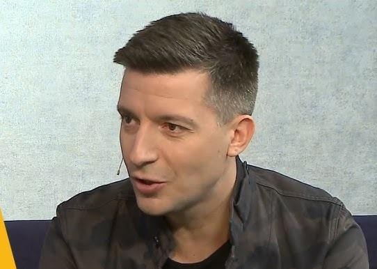 Michał Cessanis podczas inspirującej prelekcji o podróżach, z ekranem prezentującym egzotyczne miejsca w tle.