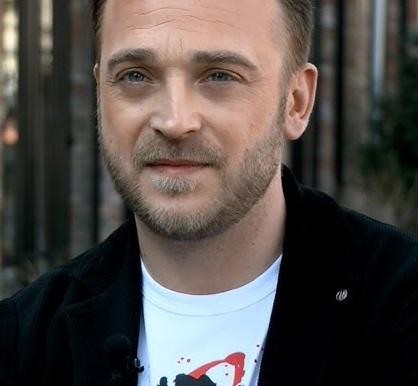 Mateusz Gessler w akcji, w kuchni, prezentujący danie.