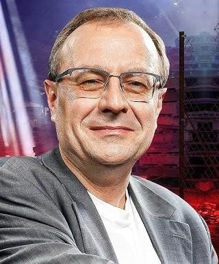 Antoni Dudek podczas wystąpienia publicznego, z widoczną ekspresją i zaangażowaniem, symbolizującą jego rolę jako popularyzatora historii i politologii.