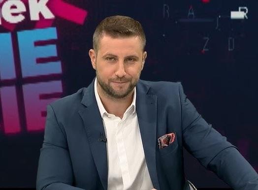 Miłosz Kłeczek podczas gorącej dyskusji w studiu telewizyjnym, gestykulujący w kierunku polityka.