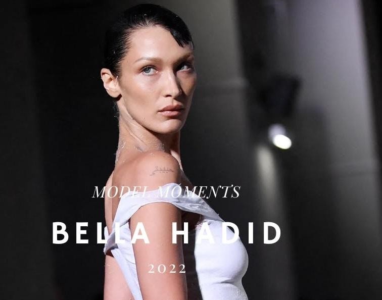Bella Hadid na wydarzeniu modowym w eleganckiej stylizacji, patrząca w obiektyw.